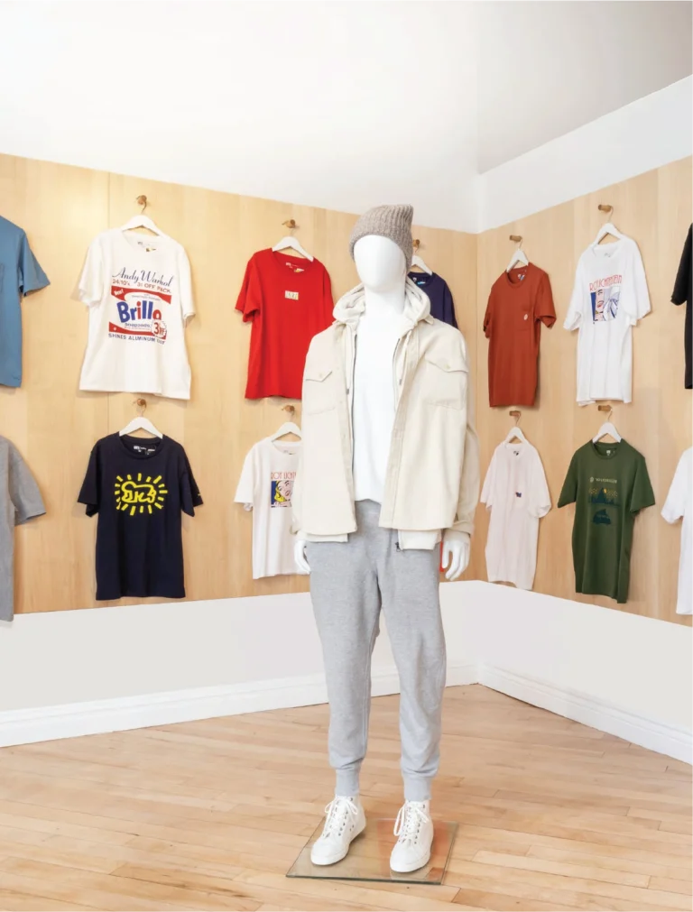 Interior design of a fashion showroom with a mannequin wearing casual clothes, surrounded by various T-shirts hanging on the walls