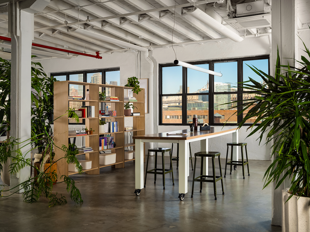Modern office design in NYC showing open common space with high ceilings and large windows with a lot of natural light